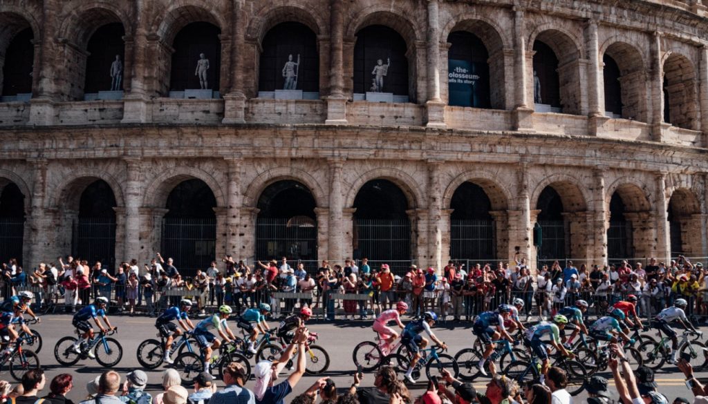 Pelotón de ciclistas en el Giro de Italia 2024 pasando por el Coliseo Romano