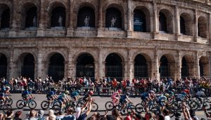 Pelotón de ciclistas en el Giro de Italia 2024 pasando por el Coliseo Romano